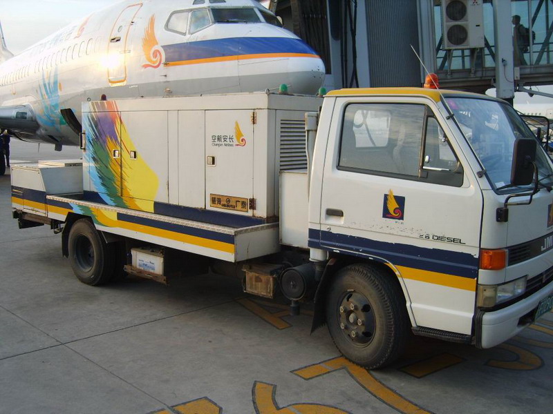 以中型卡车地盘为基础的地面电源车，它正在为海南航空的波音B737-300飞机提供地面电源，注意车辆停放方向及与飞机的相对位置，廊桥上的客人已经开始登机