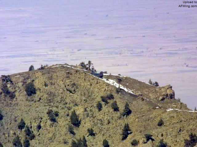 塔克盖尔山的山峰和那架被击落的MH-47E，基地组织和塔利班武装分子的碉堡以及树林线就在这架支奴干的正前方
